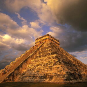 A mesmerizing view of the ancient ruins of Chichen Itza against a backdrop of lush greenery.