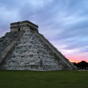 A mesmerizing view of the ancient ruins of Chichen Itza against a backdrop of lush greenery.
