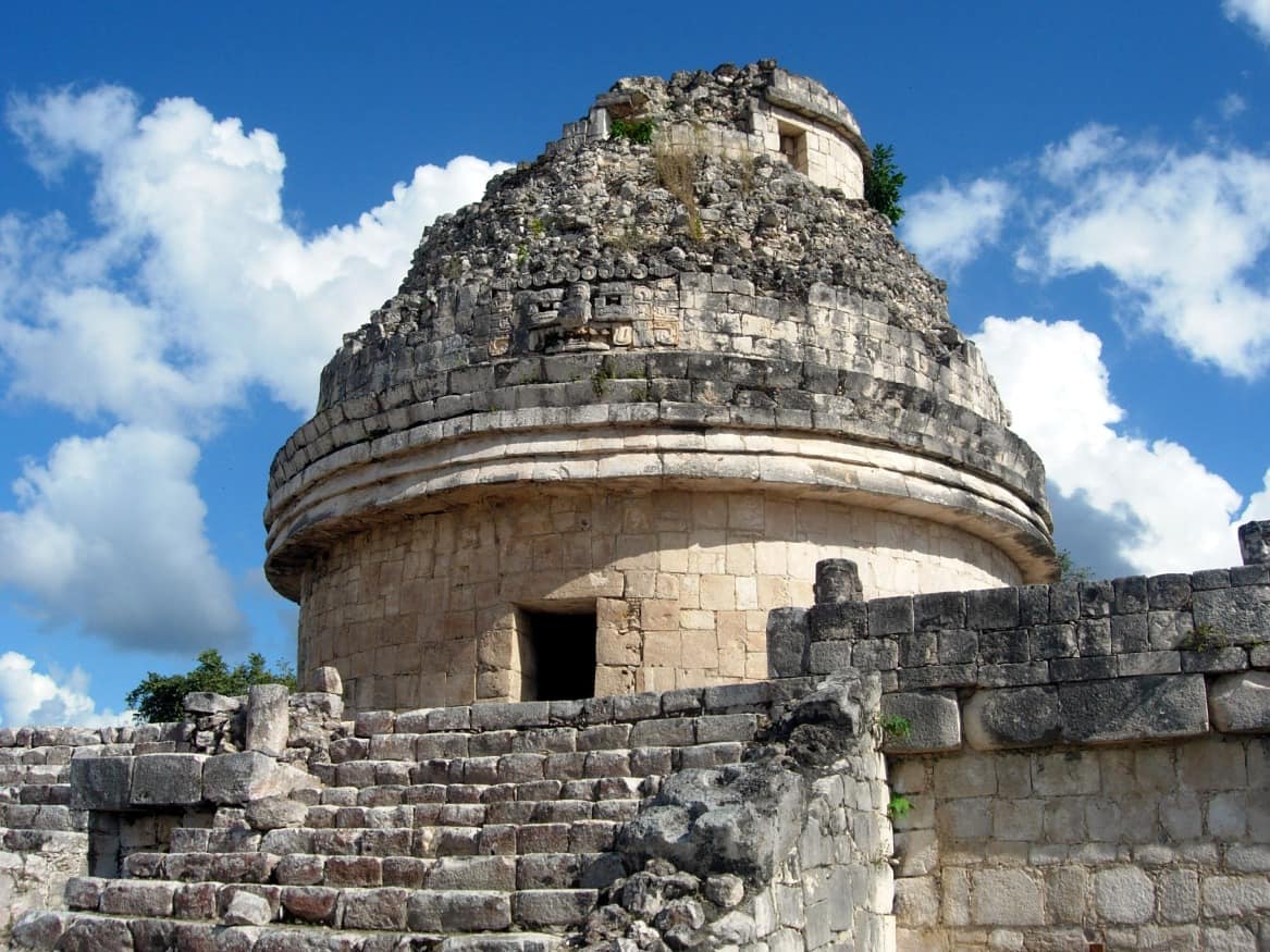 A mesmerizing view of the ancient ruins of Chichen Itza against a backdrop of lush greenery.